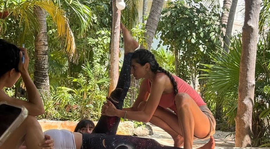 Stephania adjusting a student's raised leg during an outdoor session
